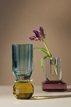 two vases with flowers in them sitting on a table next to each other,