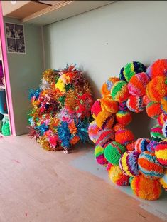 two colorful wreaths sitting next to each other on a wooden floor in front of a wall