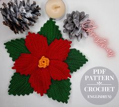 a crocheted poinsetti with pine cones and candles on top of it