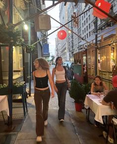 two women walking down the street in front of some buildings