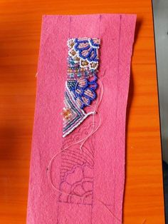 a pink piece of fabric with beading on it sitting on top of a wooden table