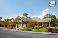 an outside view of a restaurant with flowers and trees in the foreground on a sunny day