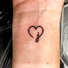 a small tattoo on the wrist of a woman with an elephant and heart in it