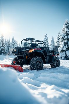 a snow plow is parked in the snow next to a utility vehicle and pine trees