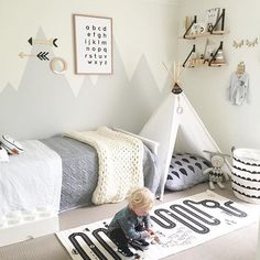 a child playing on the floor in a bedroom with a teepee tent and rug