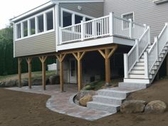 a house with stairs leading up to the front door and covered patio area next to it