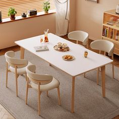 a white table with four chairs around it in front of a window and bookshelf