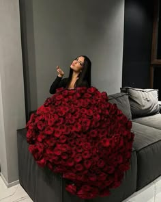 a woman sitting on top of a couch covered in red roses with her eyes closed