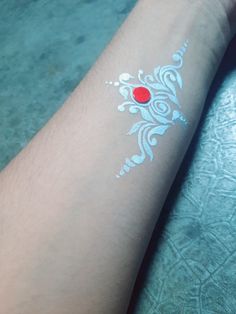 a person with a red dot on their left arm and white ink on her right arm