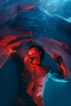 a man laying on top of a blue and red object in the water at night