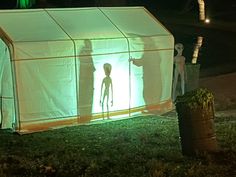 two people standing in front of a white tent with green lights on the side and behind it