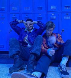 two men sitting on the ground in front of lockers