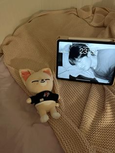 a cell phone sitting on top of a bed next to a small stuffed animal cat