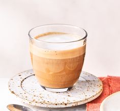 a cup of coffee sitting on top of a saucer next to a plate with a spoon