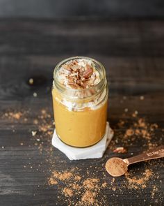 a jar filled with food sitting on top of a wooden table next to a spoon