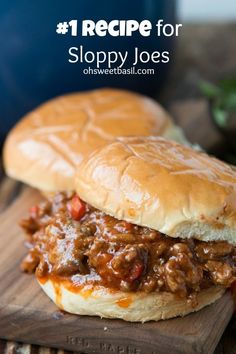 two sloppy joe sandwiches sitting on top of a wooden cutting board next to each other