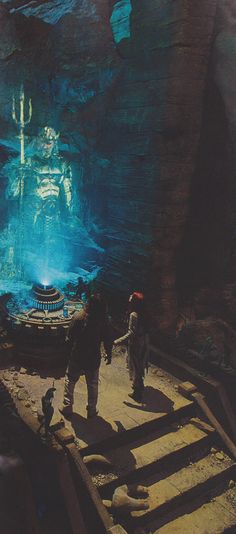 two people are standing in front of a large underwater cave with stairs leading up to it