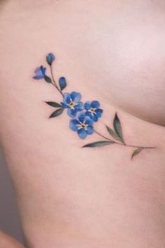 a blue flower tattoo on the side of a woman's stomach