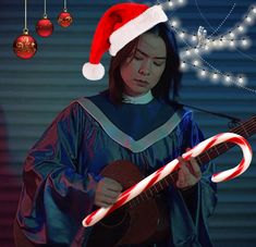 a woman wearing a santa hat playing a guitar with candy canes in front of her