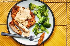 a white plate topped with meat and broccoli on top of a yellow tile floor