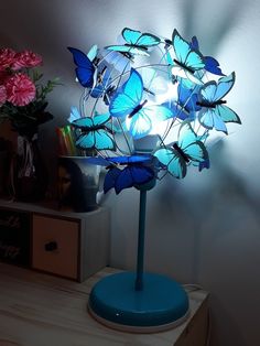 a blue lamp with butterflies on it sitting on a table next to flowers and a vase