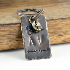 a metal keychain with an arrow on it sitting on top of a wooden box