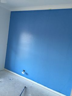 an empty room with blue walls and white paint on the wall is being worked on