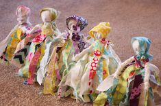 several small dolls are lined up on the floor, all dressed in different patterns and colors