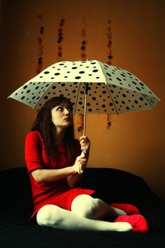 a woman sitting on a bed holding an umbrella