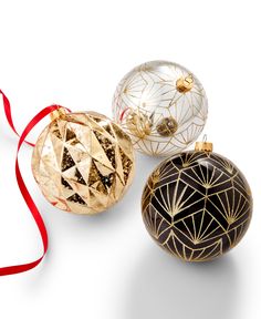 three christmas ornaments with red ribbon on white background, including one gold ornament and the other black