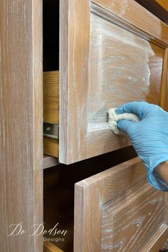 a person in blue gloves and rubber gloves cleaning wooden drawers with a cloth on their hand