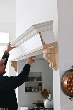 a man is working on an ornate piece of furniture in the kitchen area with his hands reaching for it