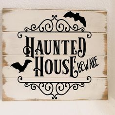 a wooden sign that says,'haunted house beware'with bats on it