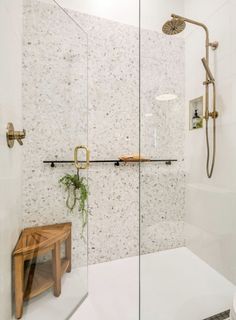 a walk in shower sitting next to a wooden bench