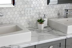 two white sinks sitting next to each other on top of a marble countertop in a bathroom