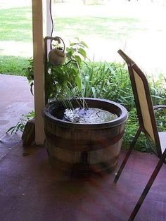 a wooden barrel filled with water sitting on top of a patio next to two chairs