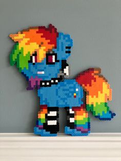 a colorful lego pony sitting on top of a white shelf next to a gray wall