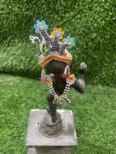 a statue is sitting in the grass with beads on it's head