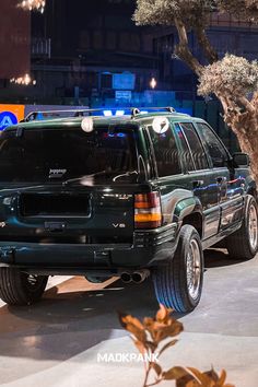 the suv is parked on the side of the road at night with its lights on