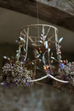 an arrangement of dried flowers in front of a metal object with strings attached to it