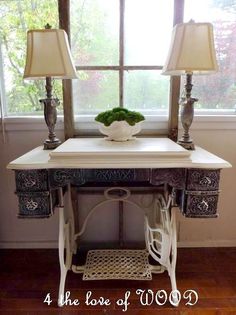 a white table with two lamps and a vase on it in front of a window