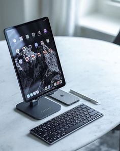 an ipad, keyboard and mouse on a white marble table in front of a window