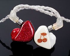 two white and red heart shaped necklaces on a black surface, one with an acrylic design