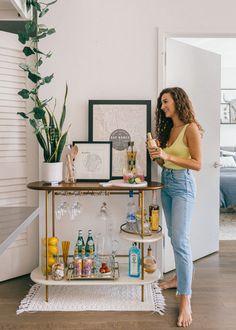 a woman standing next to a bar with drinks on it