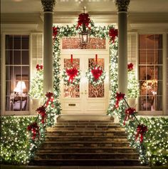 christmas lights decorate the front steps of a house with wreaths and bows on it