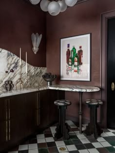 a kitchen with marble counter tops and two stools in front of a painting on the wall