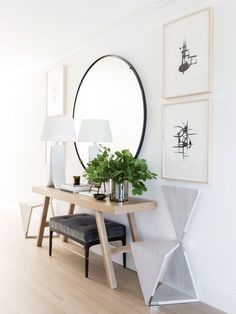 a table with a mirror and some plants on it in front of a white wall