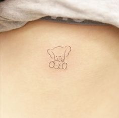 a small teddy bear tattoo on the back of a woman's left ribcage