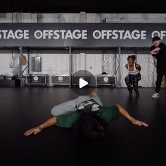 a group of people standing and sitting in front of a stage with one person laying on the floor