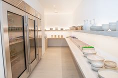 there are many plates and bowls on the shelves in this room, all lined up